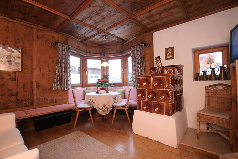 Living room with tiled stove in the Alice holiday home in Seefeld